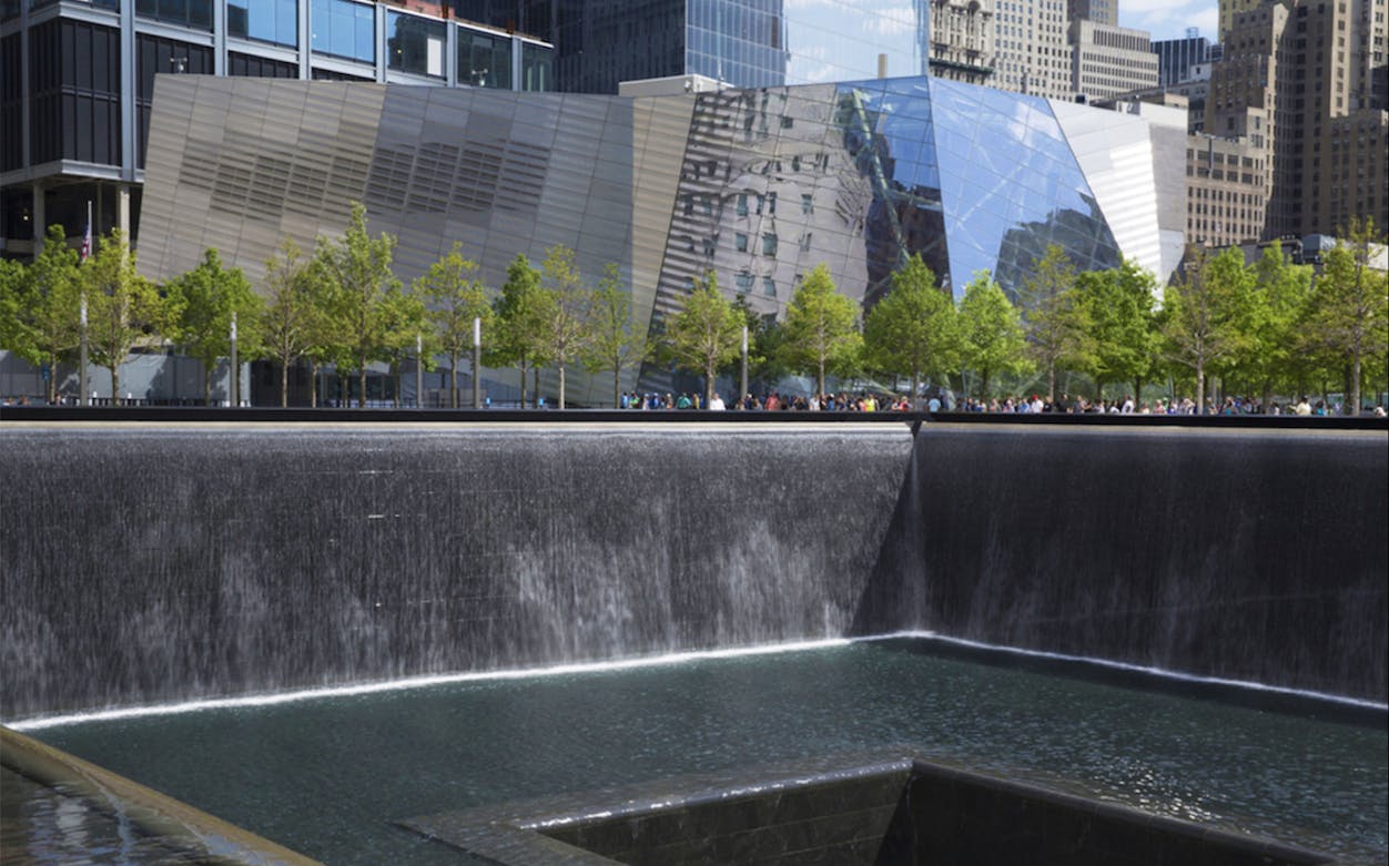 Ground Zero Memorial reflecting pool with surrounding trees and modern buildings in New York City.