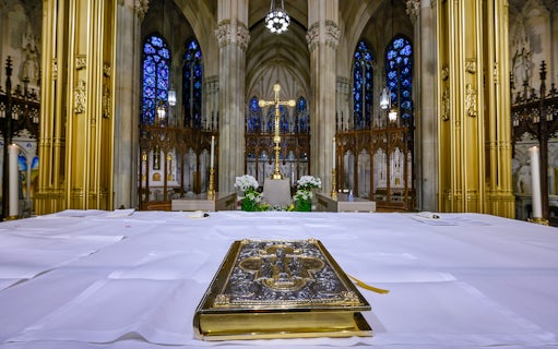 Altar view inside St Patrick's Cathedral, New York, with ornate Bible and stained glass windows.