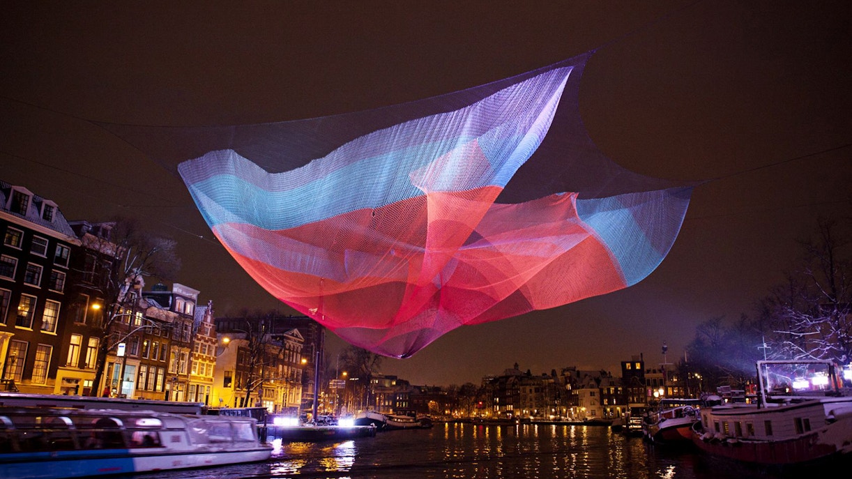 Colorful light installation over Amsterdam canal during Light Festival.