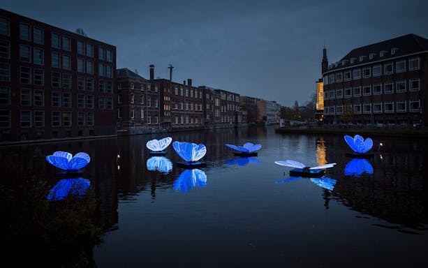 Floating blue light installations on Amsterdam canal during Light Festival.