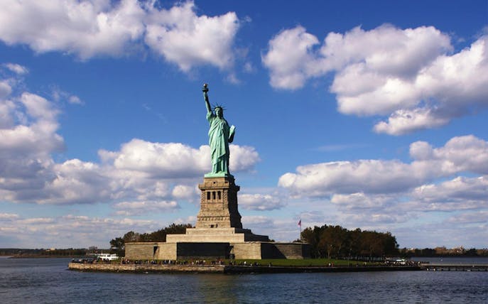 Statue of Liberty on Liberty Island, New York City, with blue sky and clouds.