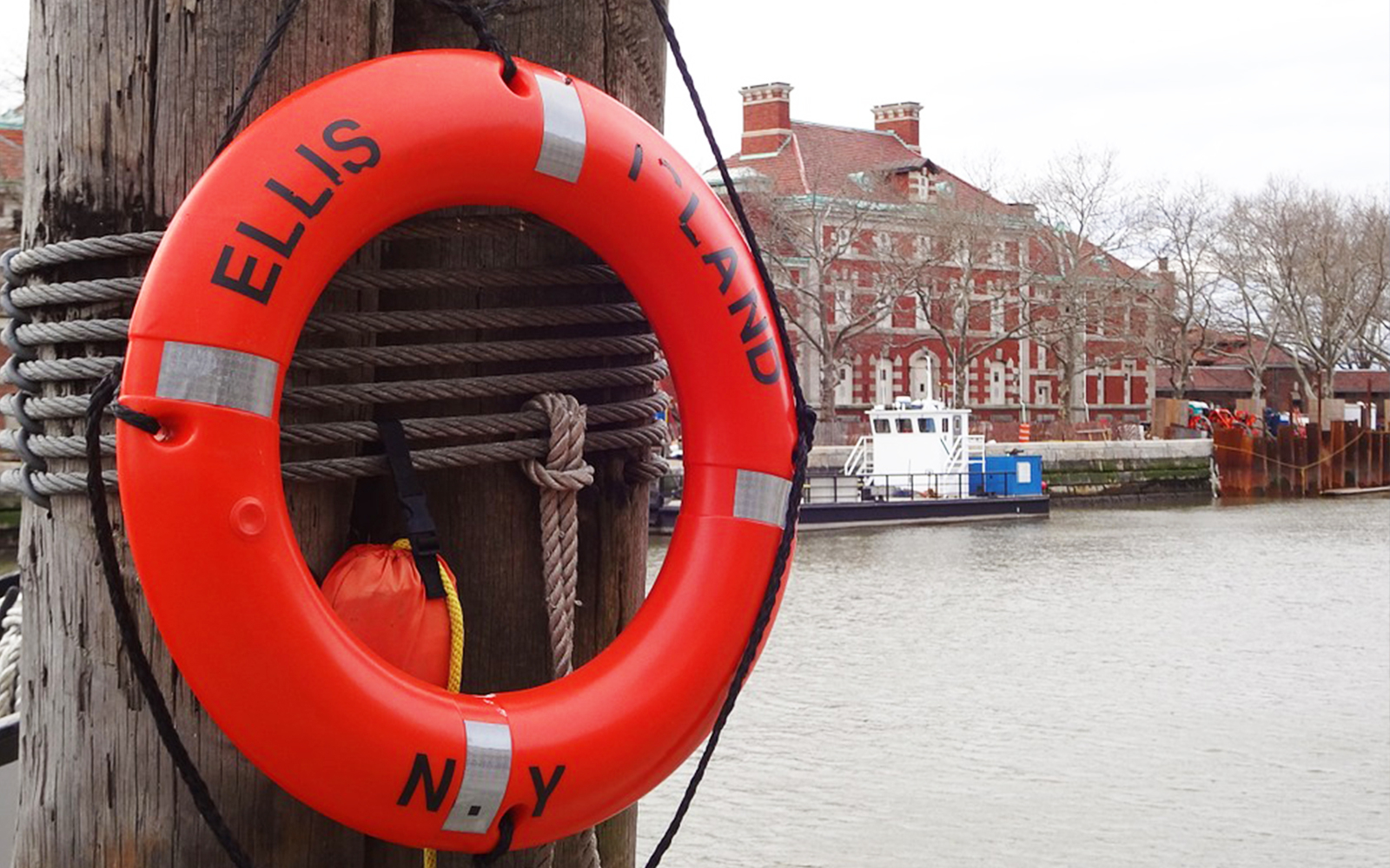 Ellis Island lifebuoy with historic building and ferry in the background.