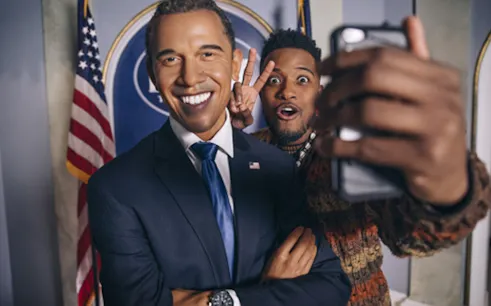 Man taking selfie with wax figure at Madame Tussauds NYC.