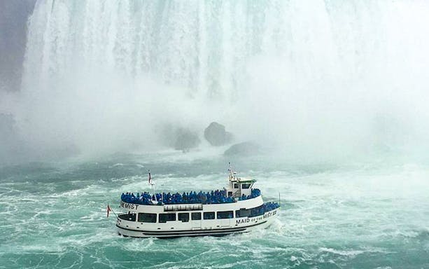 Maid of the Mist boat near Niagara Falls, USA, surrounded by mist and water.