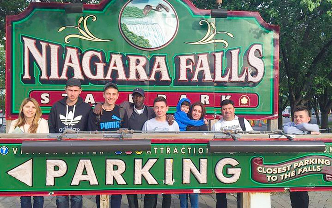 Group of tourists at Niagara Falls State Park sign, USA.