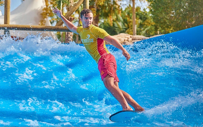 Surfer riding wave at Aquaventure Waterpark, Dubai.