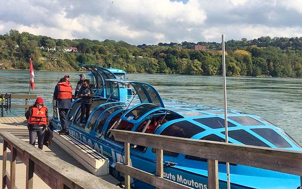 Jet boat docked at Niagara River with passengers preparing for USA side sightseeing tour.