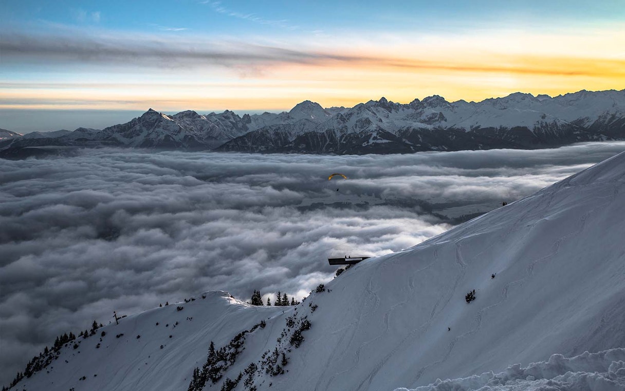 Snowy mountain view at sunset with clouds and distant peaks in Innsbruck.