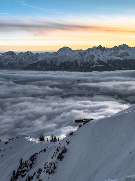 Snowy mountain view at sunset with clouds and distant peaks in Innsbruck.