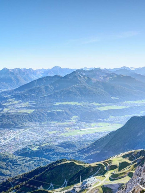 Innsbruck cityscape and surrounding Alps viewed from mountain peak.