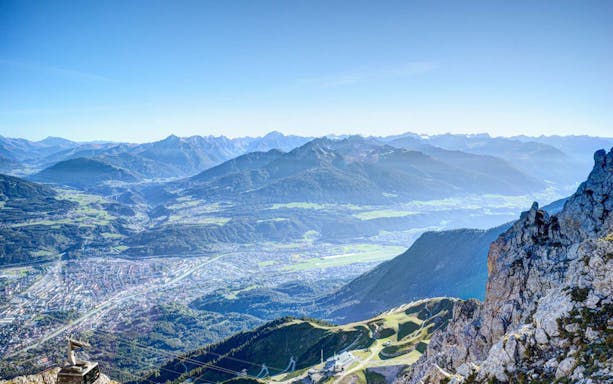 Innsbruck cityscape and surrounding Alps viewed from mountain peak.