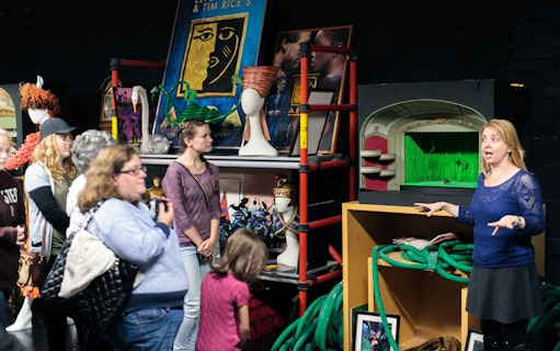 Group touring New Amsterdam Theatre's backstage with Disney props and guide.