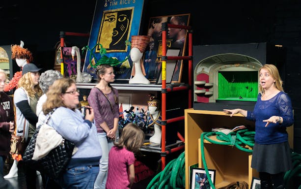 Group touring New Amsterdam Theatre's backstage with Disney props and guide.