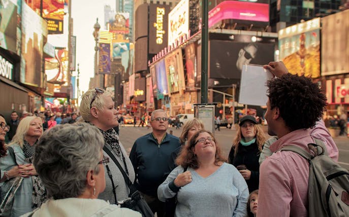 Group tour in Times Square, New York City, led by a guide for the Disney on Broadway experience.