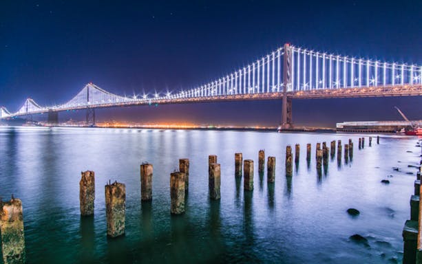 San Francisco Bay Bridge illuminated at night during a bay cruise.
