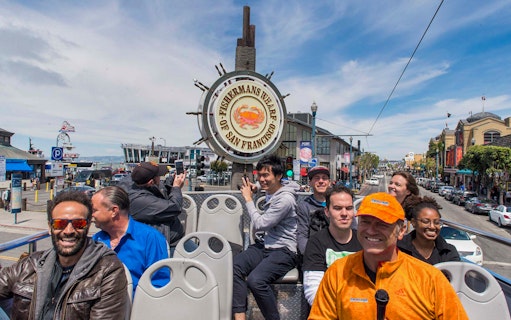 Tourists on an open-top bus at Fisherman's Wharf, San Francisco, during a city tour.
