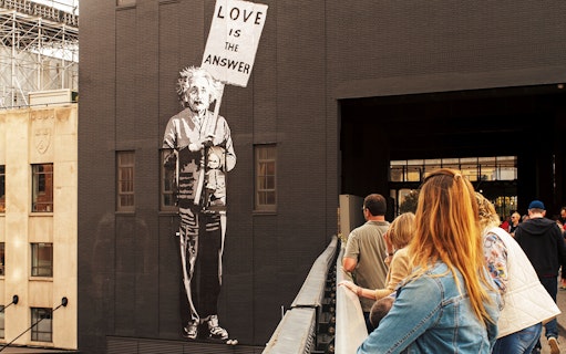 Mural of a figure holding a "Love is the Answer" sign on the High Line, New York City.
