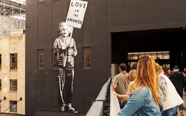 Mural of a figure holding a "Love is the Answer" sign on the High Line, New York City.