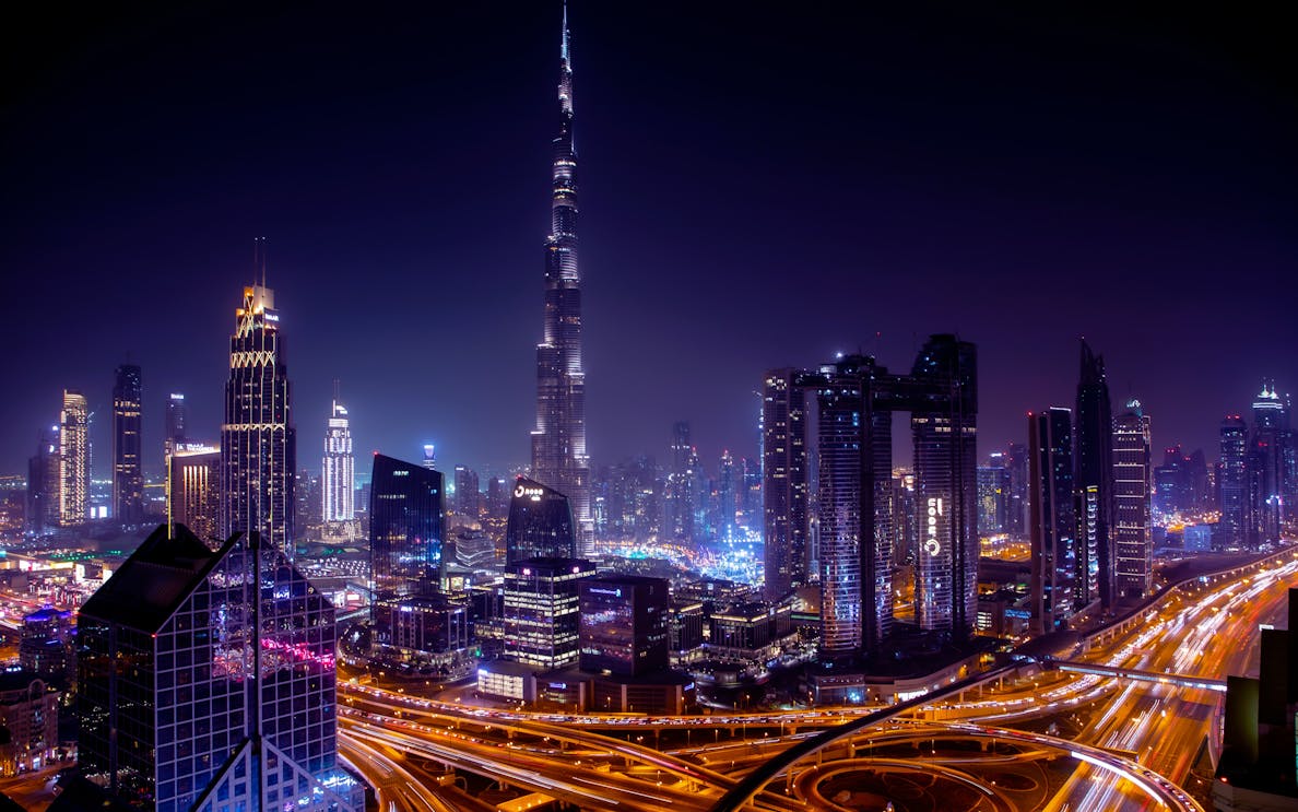 Dubai skyline at night featuring Burj Khalifa and illuminated cityscape.