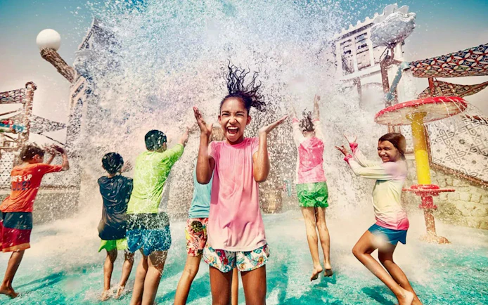 Children playing under water splash at Yas Waterworld Abu Dhabi.