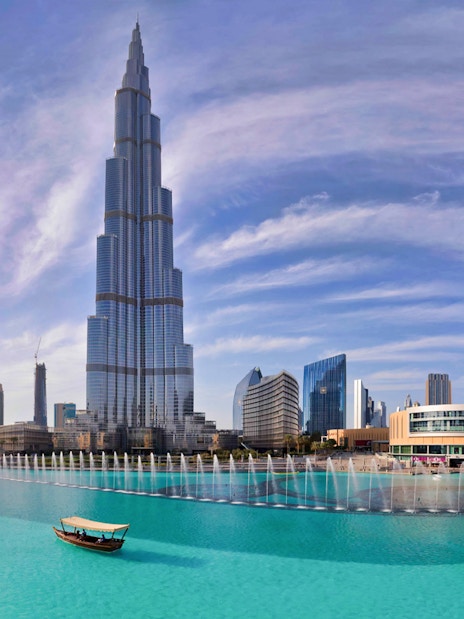 Burj Khalifa towering over Dubai Fountain with a boat on the water.