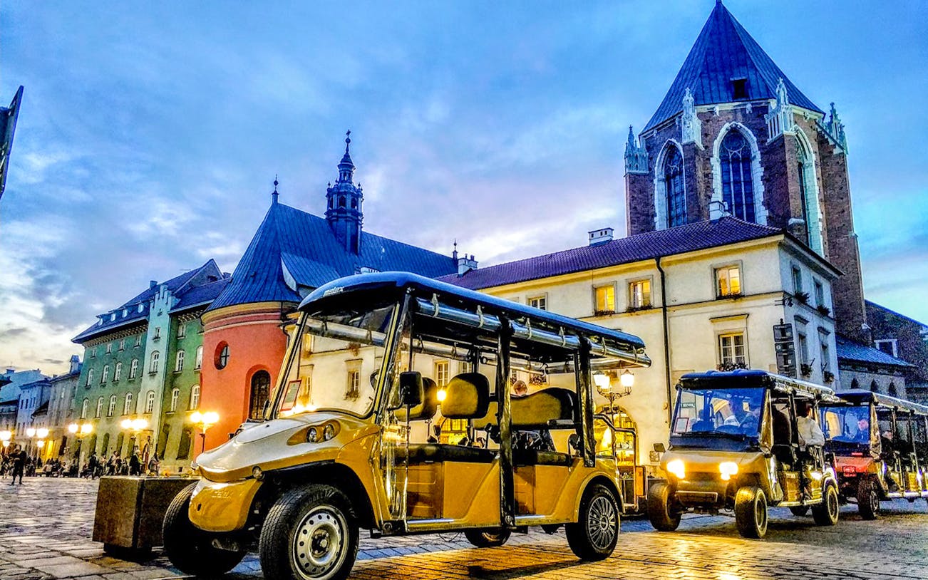 Golf carts in Krakow's Kazimierz Quarter near historic buildings at dusk.