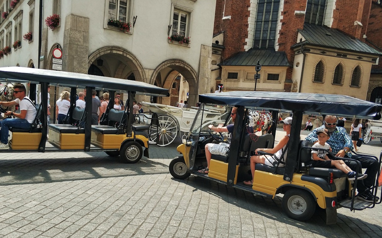 Golf carts touring Krakow's Old Town near historic buildings.