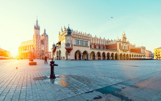 Krakow's Main Square with St. Mary's Basilica and Cloth Hall at sunrise.