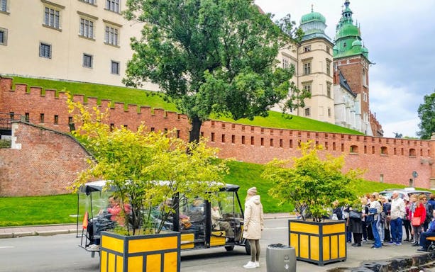 Golf cart tour near Wawel Castle, Krakow, with tourists and historic architecture.