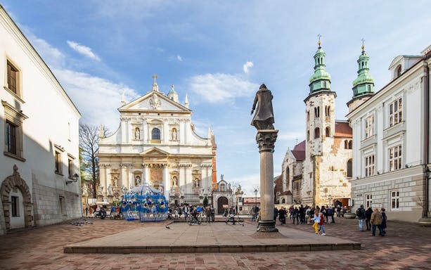 Krakow Old Town square with historic church and tourists, part of golf cart tour.