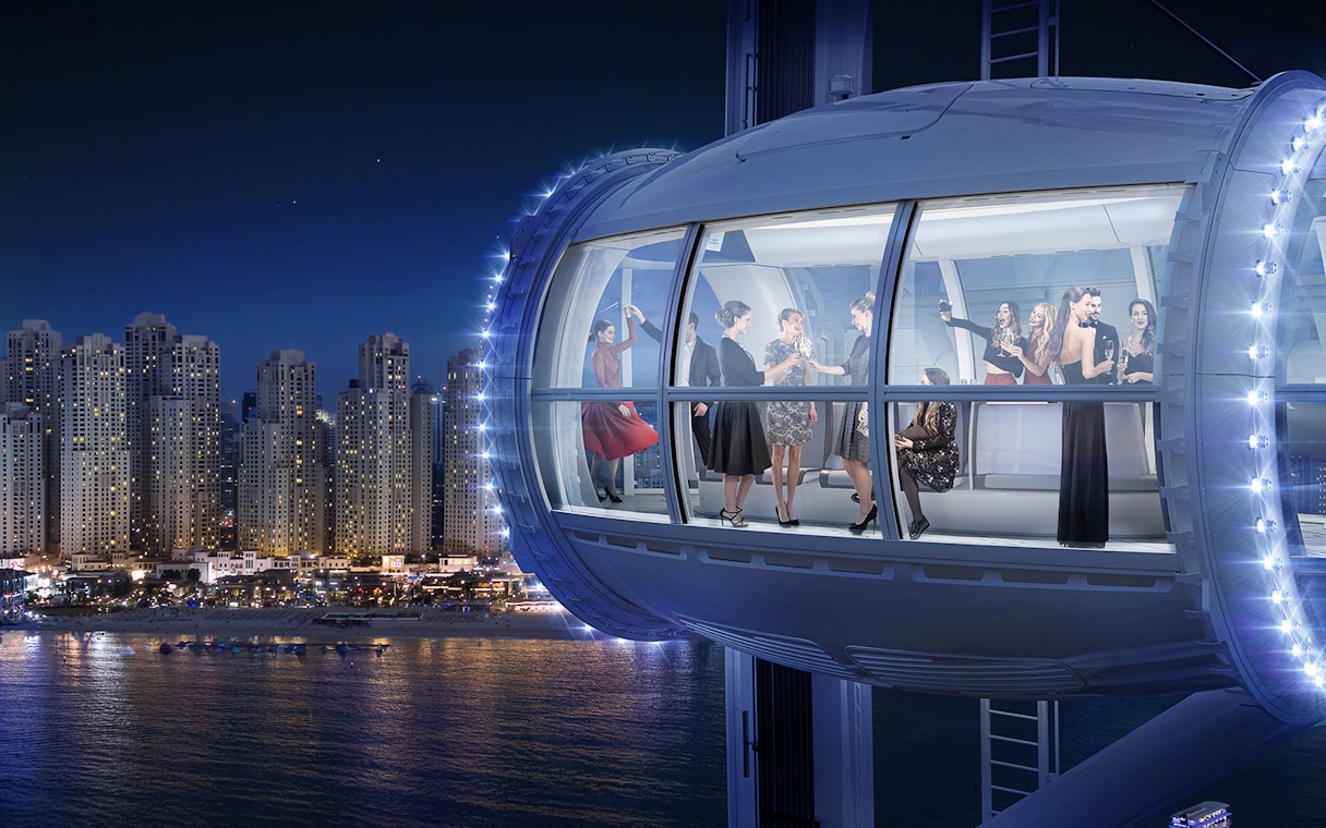Ain Dubai observation cabin with people enjoying city skyline views at night.