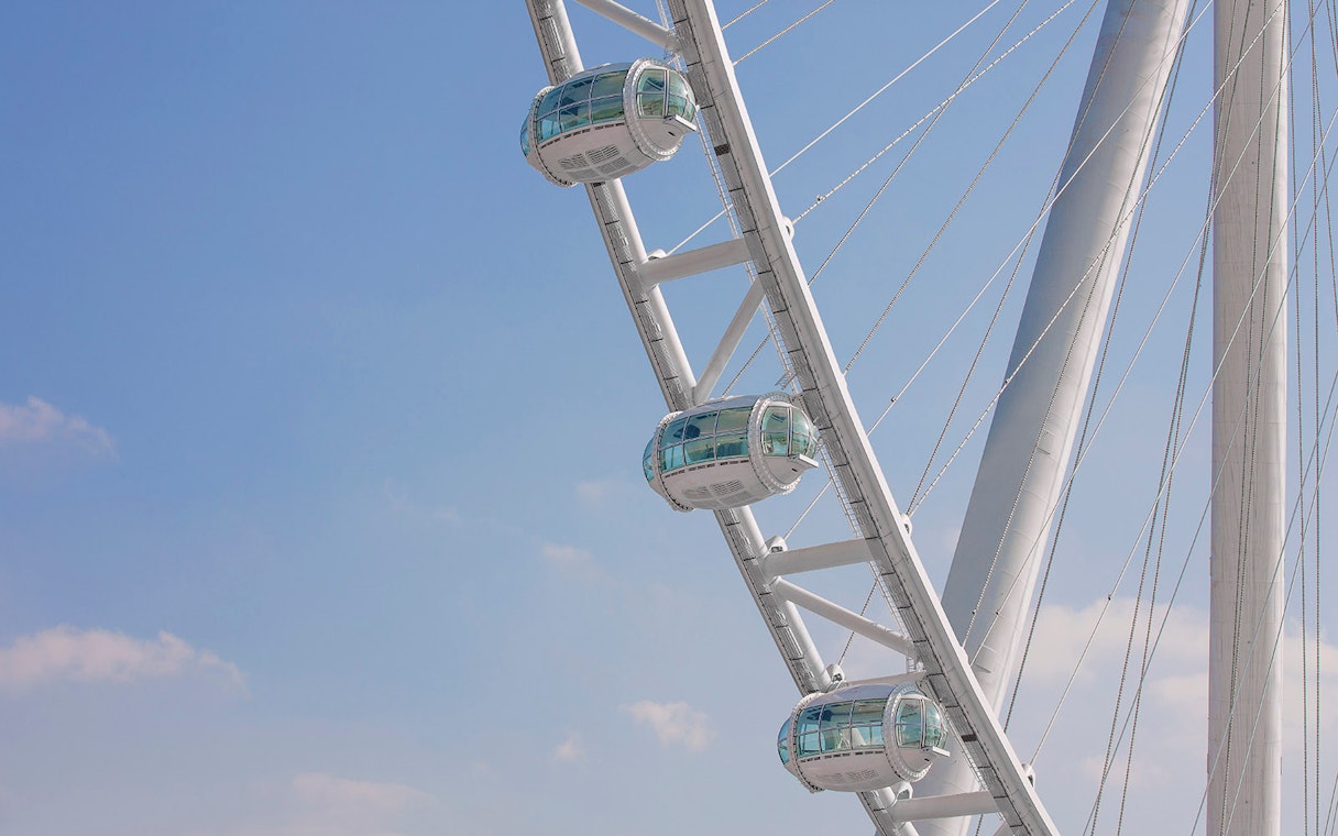 Ain Dubai observation wheel cabins against a clear blue sky.
