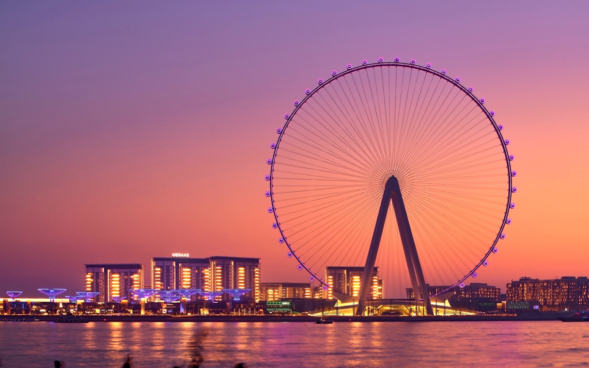 Ain Dubai Ferris wheel at sunset with city skyline in the background.