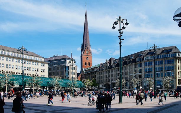 Reeperbahn street view in Hamburg's Wischen Hafen, with St. Michael's Church and Rathaus in the background.