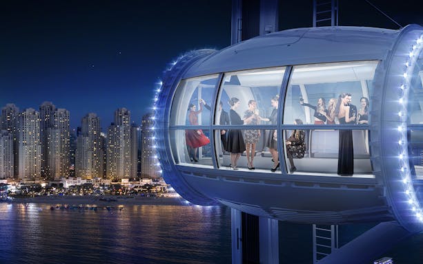 Ain Dubai observation cabin with people enjoying city skyline views at night.