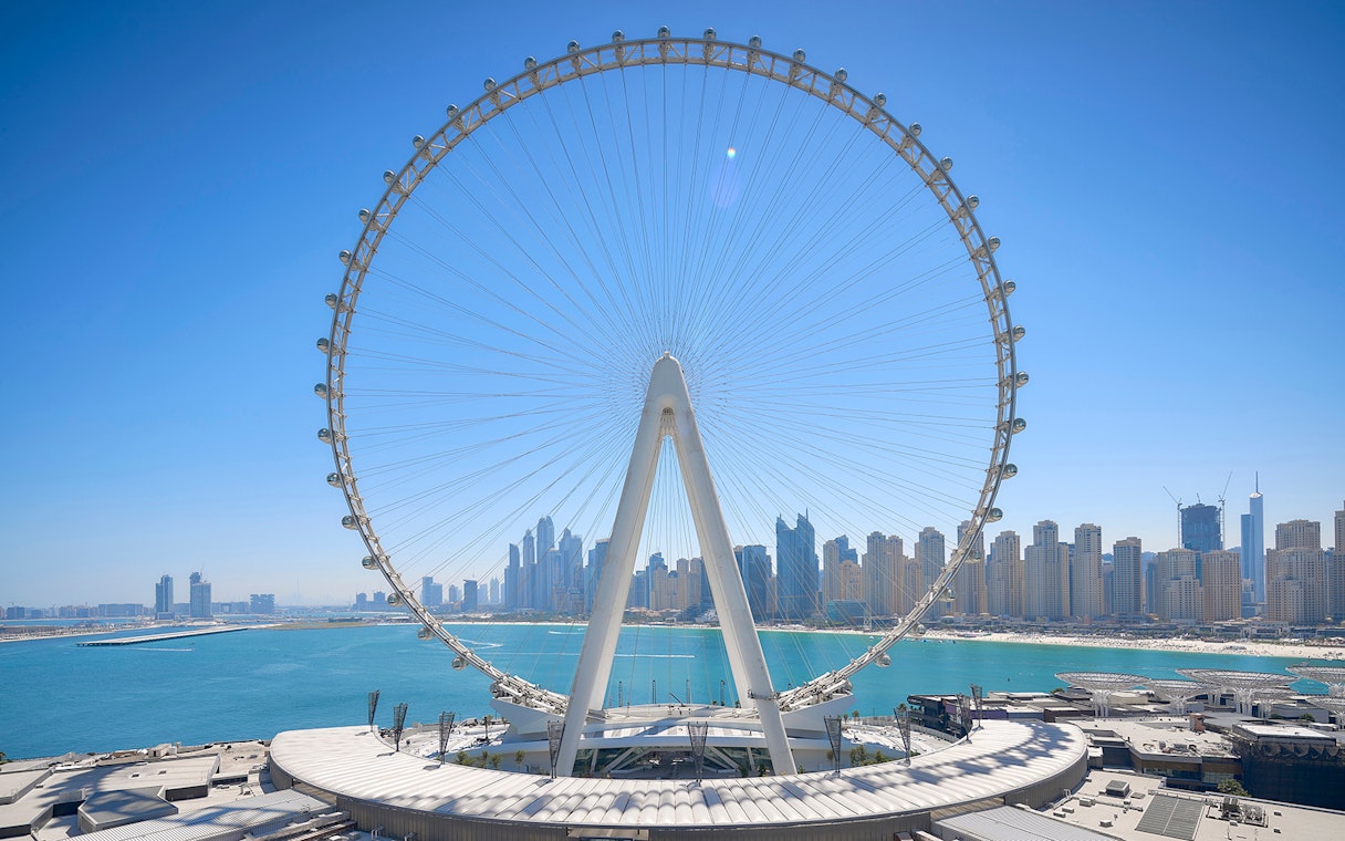 Ain Dubai Ferris wheel with city skyline and sea in the background.