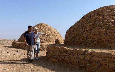 Couple exploring ancient stone tombs at Al Ain Zoo, UAE.