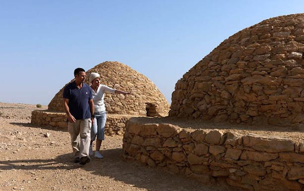 Couple exploring ancient stone tombs at Al Ain Zoo, UAE.