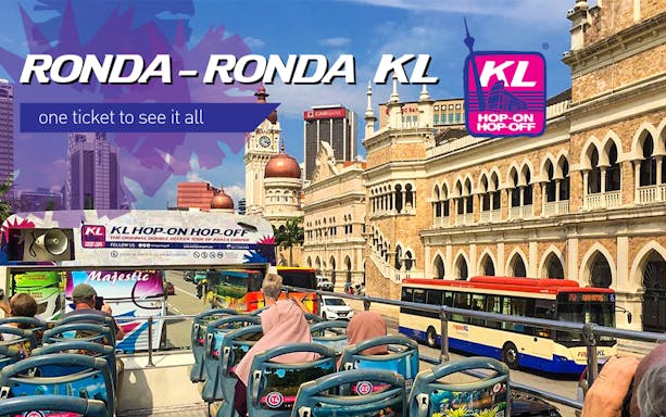 Open-top bus tour passing Sultan Abdul Samad Building in Kuala Lumpur.