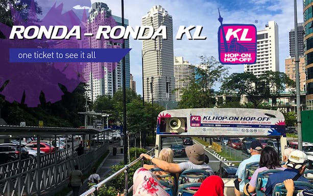 Open-top bus tour in Kuala Lumpur with city skyline in the background.