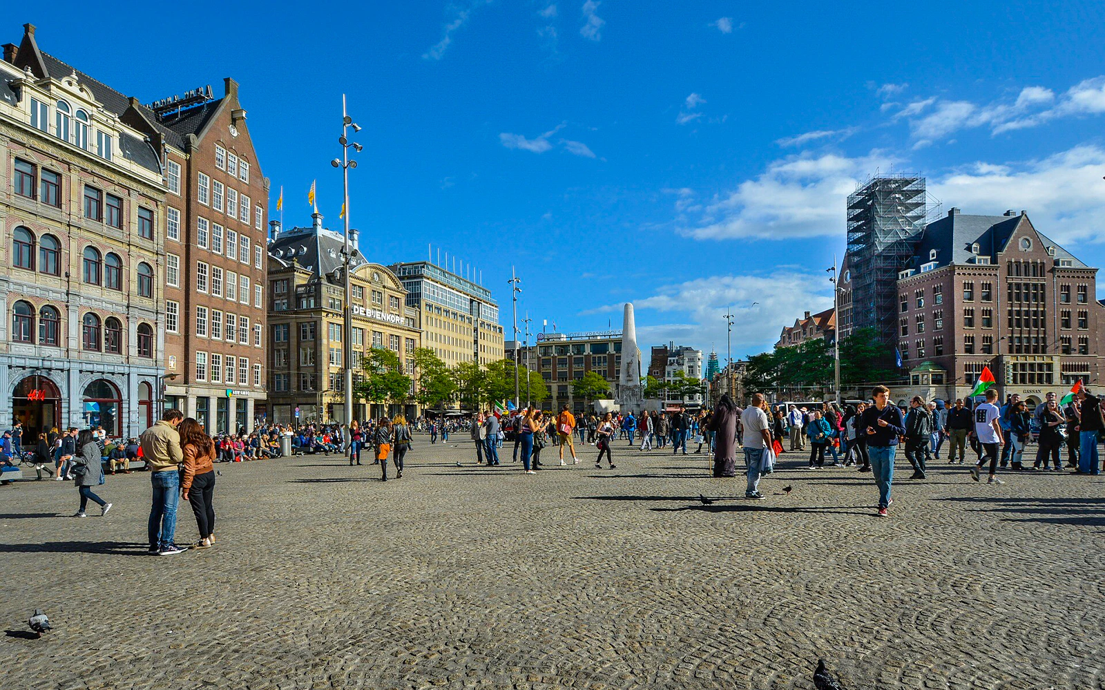 Dam Square with people walking and historic buildings, Amsterdam audio tour.