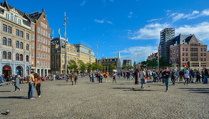 Dam Square with people walking and historic buildings, Amsterdam audio tour.