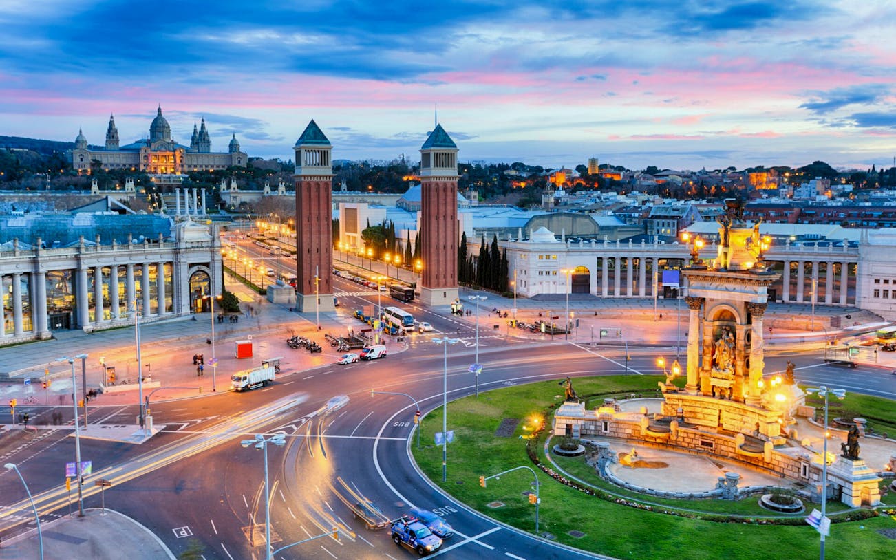 Barcelona's Plaça d'Espanya with Venetian Towers and Magic Fountain at dusk.