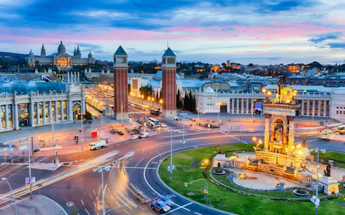 Barcelona's Plaça d'Espanya with Venetian Towers and Magic Fountain at dusk.
