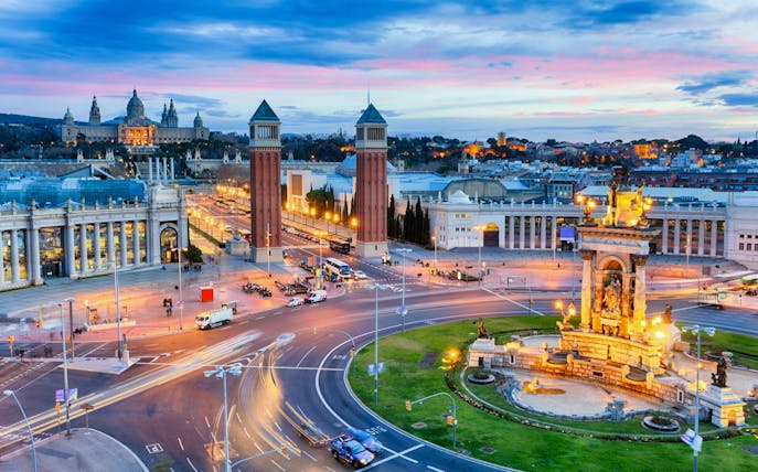 Barcelona's Plaça d'Espanya with Venetian Towers and Magic Fountain at dusk.
