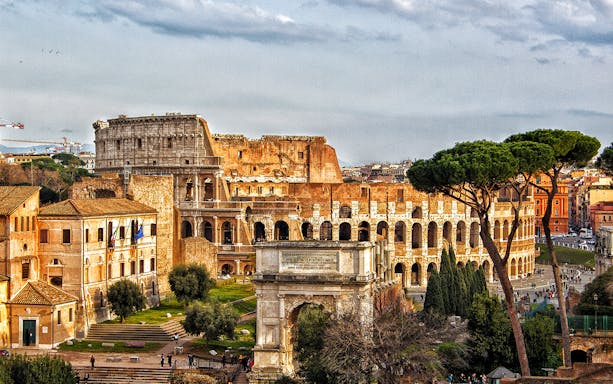 Colosseum in Rome with view of arena floor and Arch of Constantine.