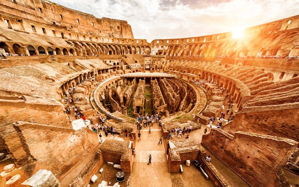 Colosseum interior view with visitors on the arena floor, Rome, Italy.