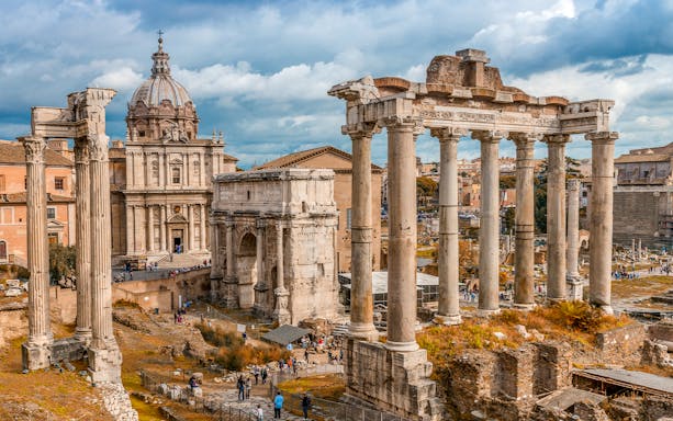 Roman Forum ruins with ancient columns and arch, Rome, near Colosseum.