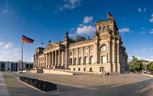 Reichstag building in Berlin with German flags, part of a self-guided audio tour.