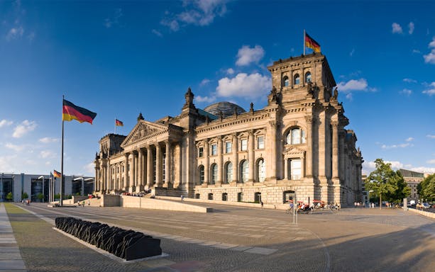 Reichstag building in Berlin with German flags, part of a self-guided audio tour.